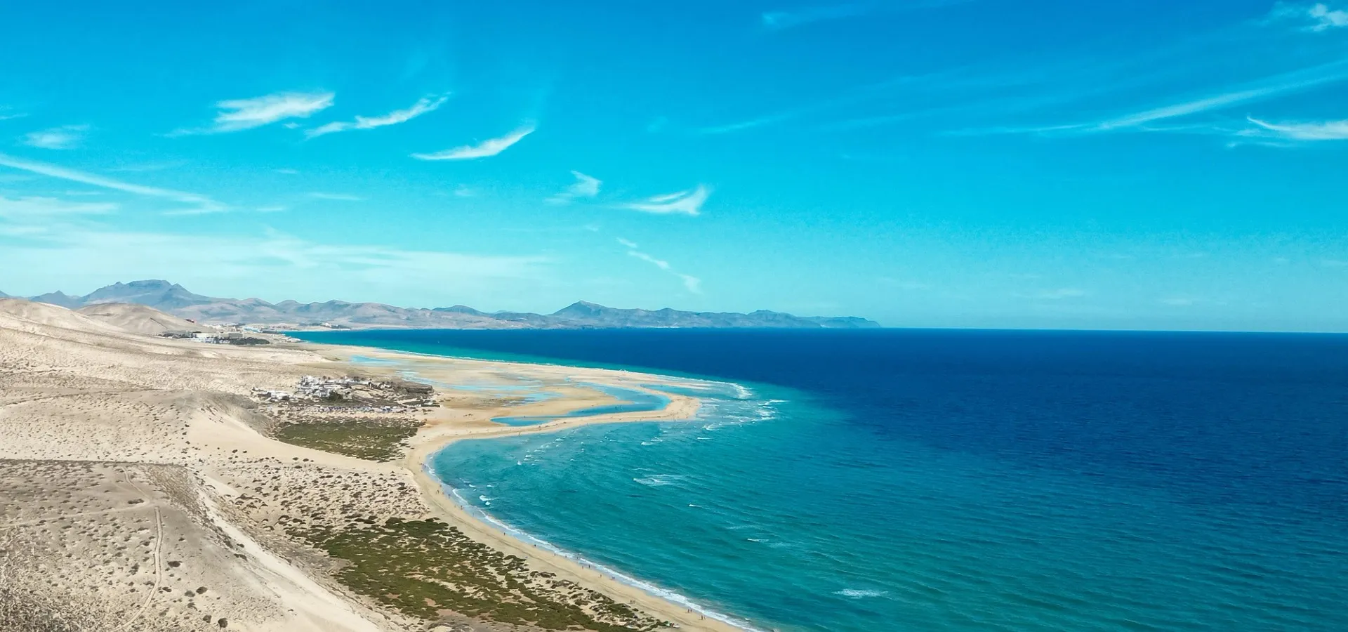 Türkisfarbenes Wasser an der Küste von Fuerteventura mit Blick auf Strand, Berge und Meer